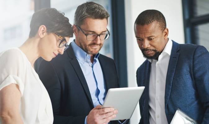 Kapitalanleger beraten sich zu Immobilieninvestments bei der SDH-Immobilien GmbH & Co. KG Drei Geschäftsleute betrachten gemeinsam ein Tablet und besprechen Anlagestrategien für Immobilienkapitalanlagen der SDH-Immobilien GmbH & Co. KG.