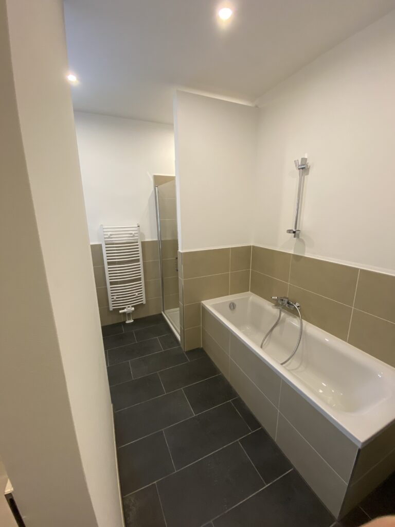 Modernes Badezimmer mit Badewanne, separater Dusche, Handtuchheizkörper und großformatigen Bodenfliesen in einer Wohnung in der Otto-Schimmel-Straße 11, angeboten von der SDH-Immobilien GmbH & Co. KG.