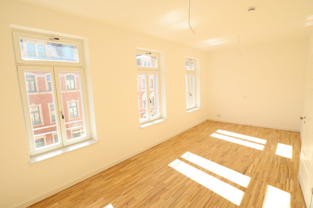 Helles, frisch renoviertes Zimmer mit hohen Fenstern, weiß gestrichenen Wänden und Parkettboden in einem Altbau an der Gießerstraße, angeboten von der SDH-Immobilien GmbH & Co. KG.