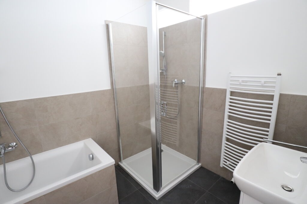 Modernes Bad mit Dusche, Badewanne, Handtuchheizkörper und hellen Wandfliesen in einer Wohnung in der Heinrich-Lorenz-Straße 11, angeboten von der SDH-Immobilien GmbH & Co. KG.