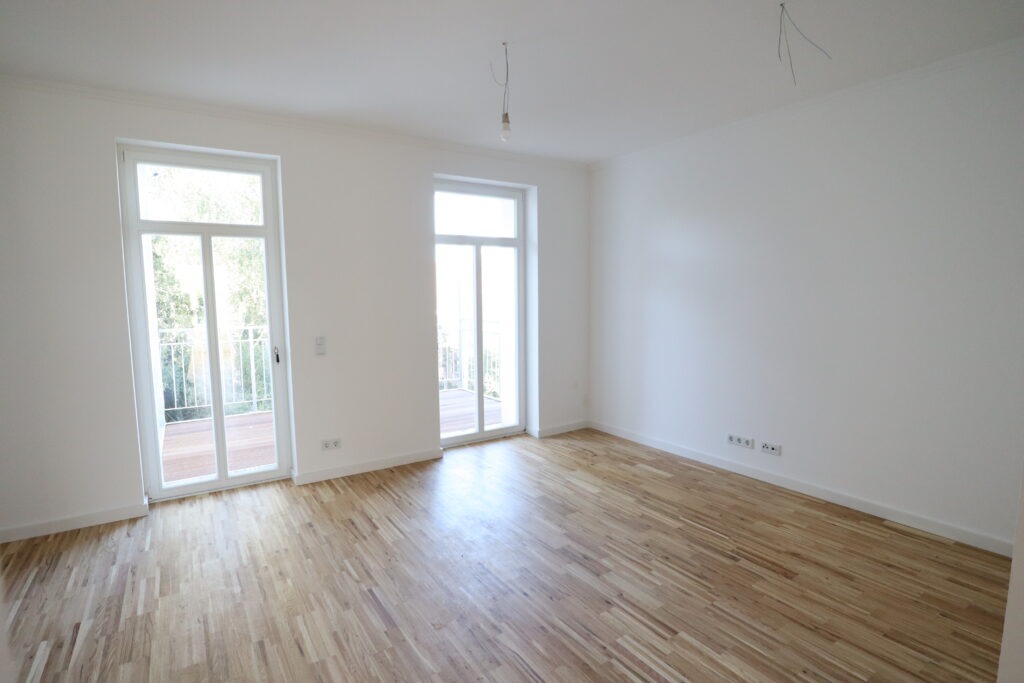 Großer, heller Wohnraum mit Parkettboden und zwei bodentiefen Fenstertüren zu einem Balkon in einer Wohnung in der Heinrich-Lorenz-Straße, angeboten von der SDH-Immobilien GmbH & Co. KG.
